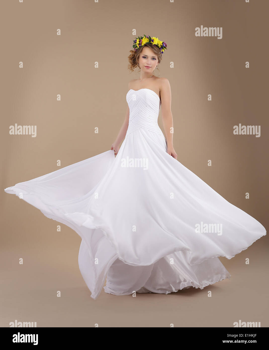 Schöne Braut mit frühlingshaften Kranz von Blumen in der Fliegerei Brautkleid Stockfoto
