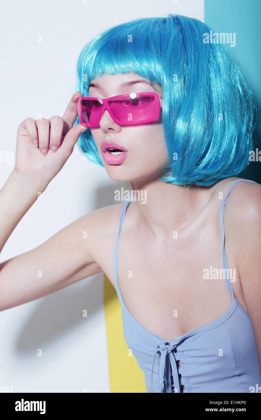 Individualität. Frau trägt blau glänzend Perücke und rosa Brille Stockfoto