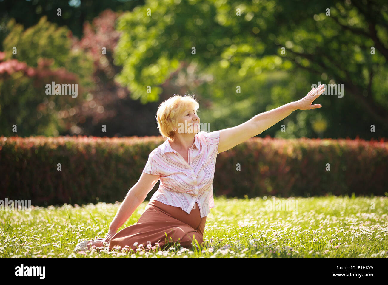 Meditation. Anmutig alte Frau im Park ihre Hand dehnen Stockfoto