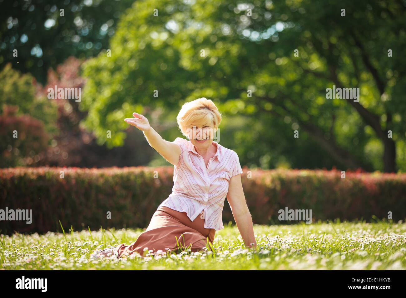 Genuss. Positive Emotionen. Ausgehende alte Frau ruht auf dem Rasen Stockfoto