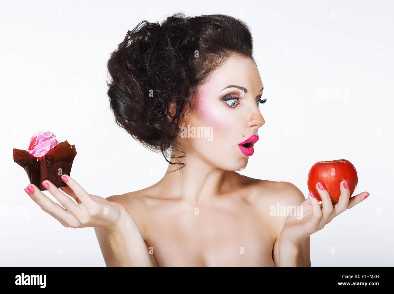 Überrascht, lustige Frau entscheidet zwischen Apple und Kuchen Stockfoto