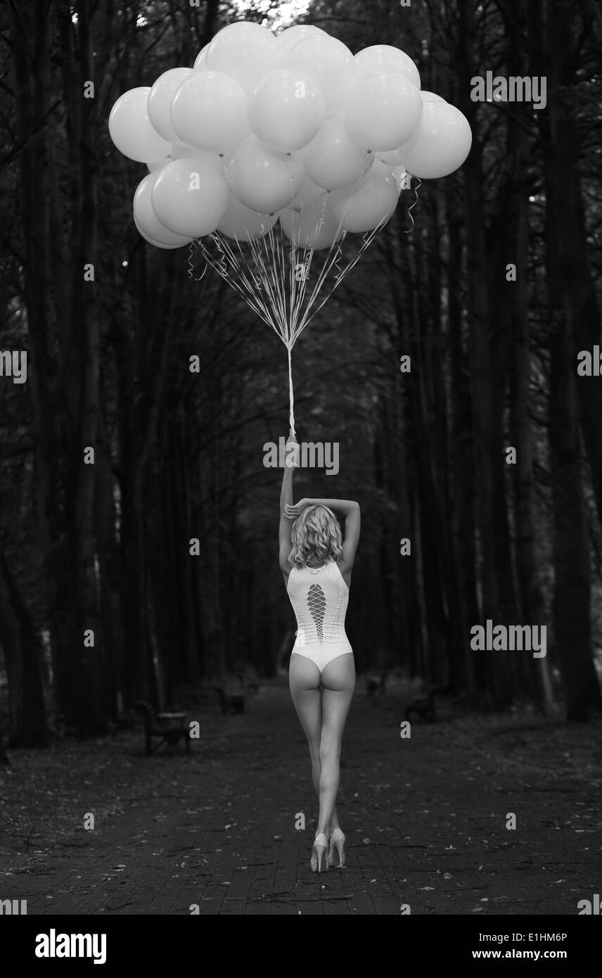 Melancholie. Einsame Frau mit Luftballons in dunklen und düsteren Wald Stockfoto