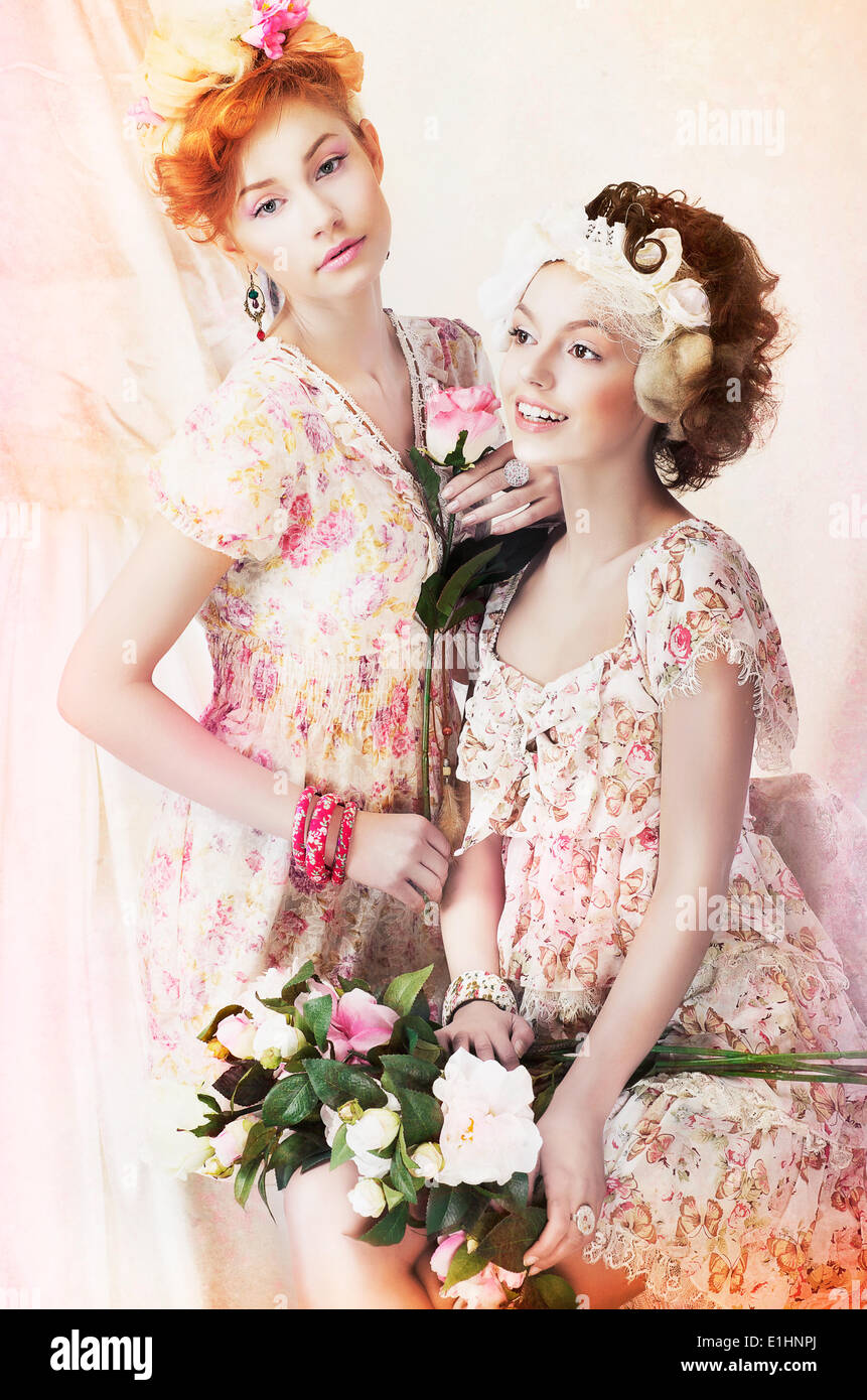 Frische. Zwei junge hübsche Frauen im klassischen Vintage-Kleider mit Blumen. Pin-Up-Stil Stockfoto