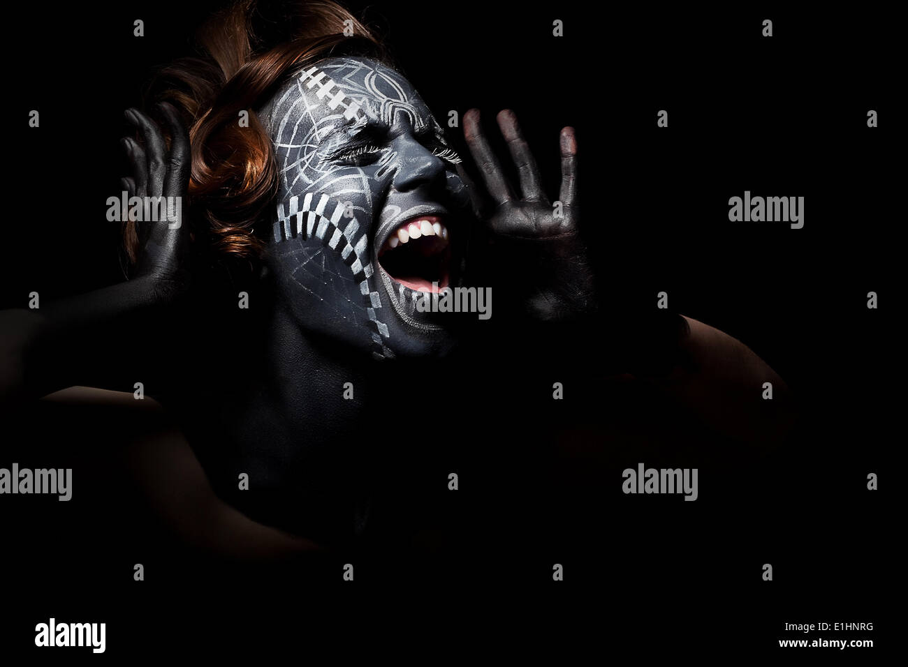 Kunstfoto einer gestressten ethnische Frau mit schwarz bemalten Maske auf Gesicht und tattoo Stockfoto