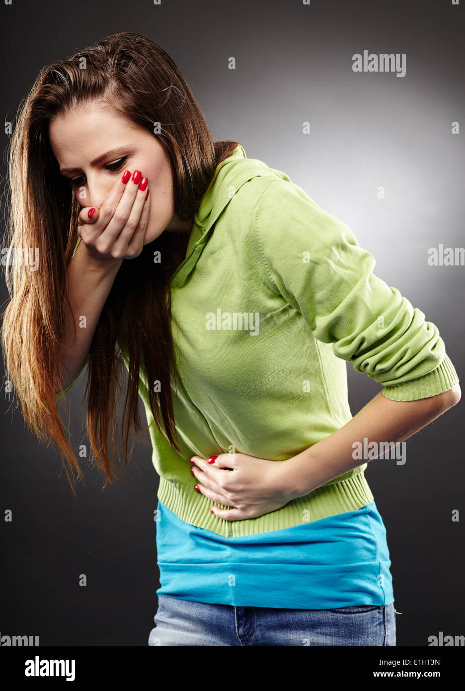 Studioaufnahme der eine kranke Frau zu halten Sie ihren Bauch über dem Kopf zusammenschlagen grauer Hintergrund Stockfoto