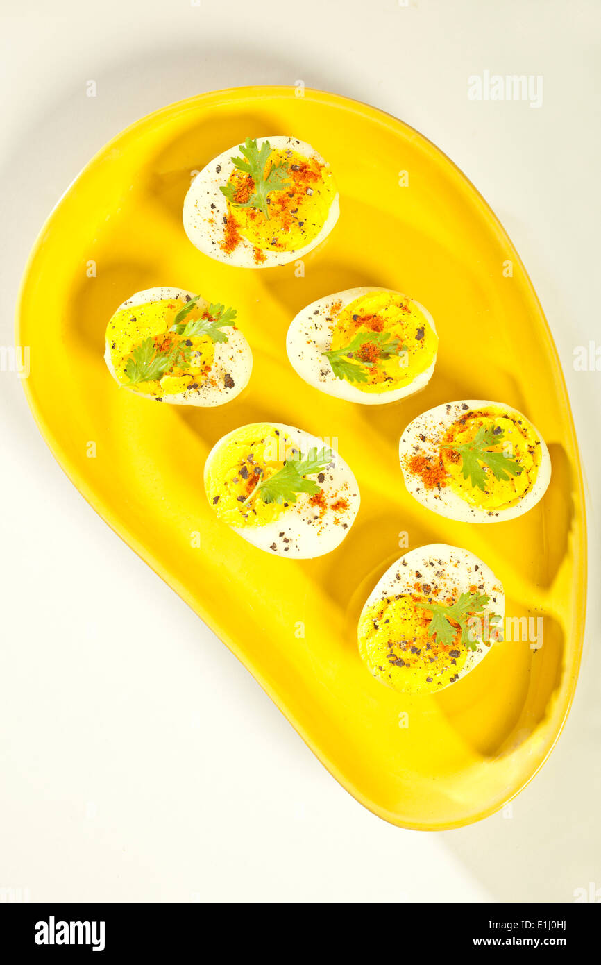 Hart gekochten Eiern, in Hälften geschnitten und auf gelbe Platte serviert Stockfoto