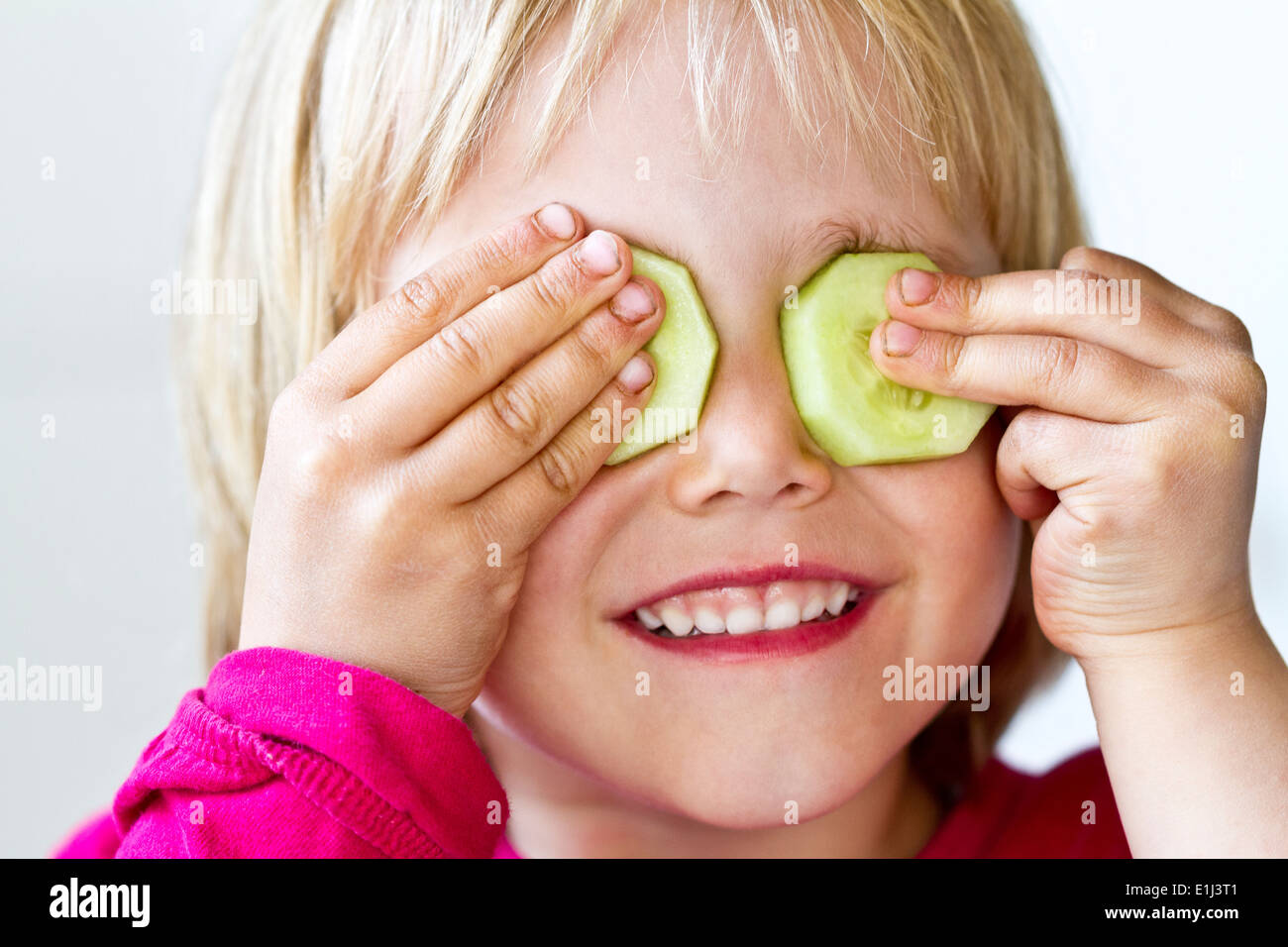 Porträt von kleinen Mädchen mit zwei Scheiben Gurke auf ihre Augen Stockfoto