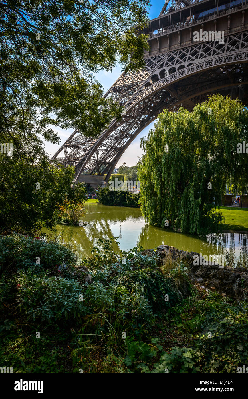 Eines des Eiffelturms Säulen Blick durch einige Bäume in einem Sommer klare Tag in Paris, Frankreich Stockfoto