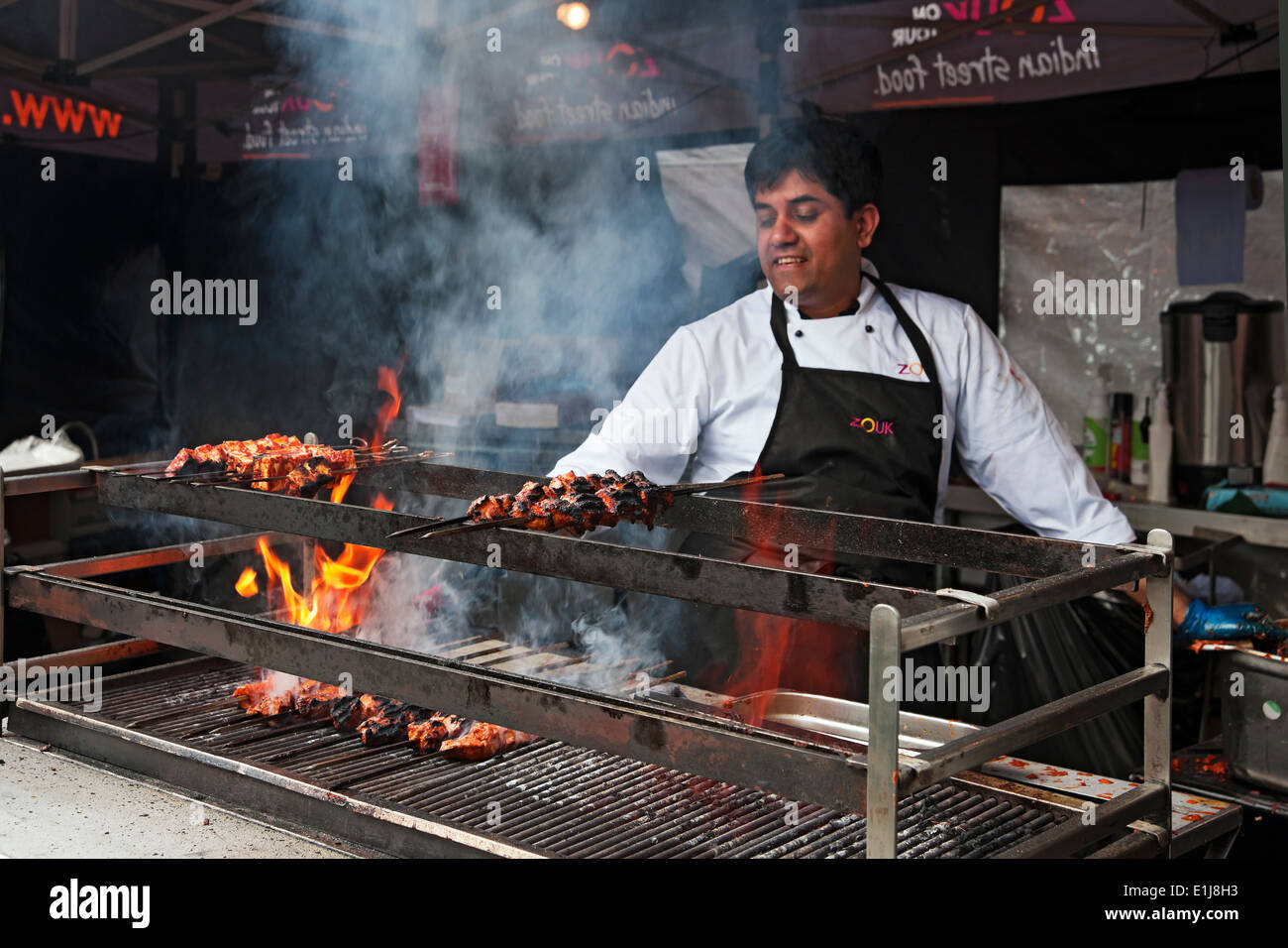 Mann Koch Kochen Fleisch auf einem Grill Flammen Indian Street Food Stand York North Yorkshire England UK Vereinigtes Königreich GB Großbritannien Stockfoto