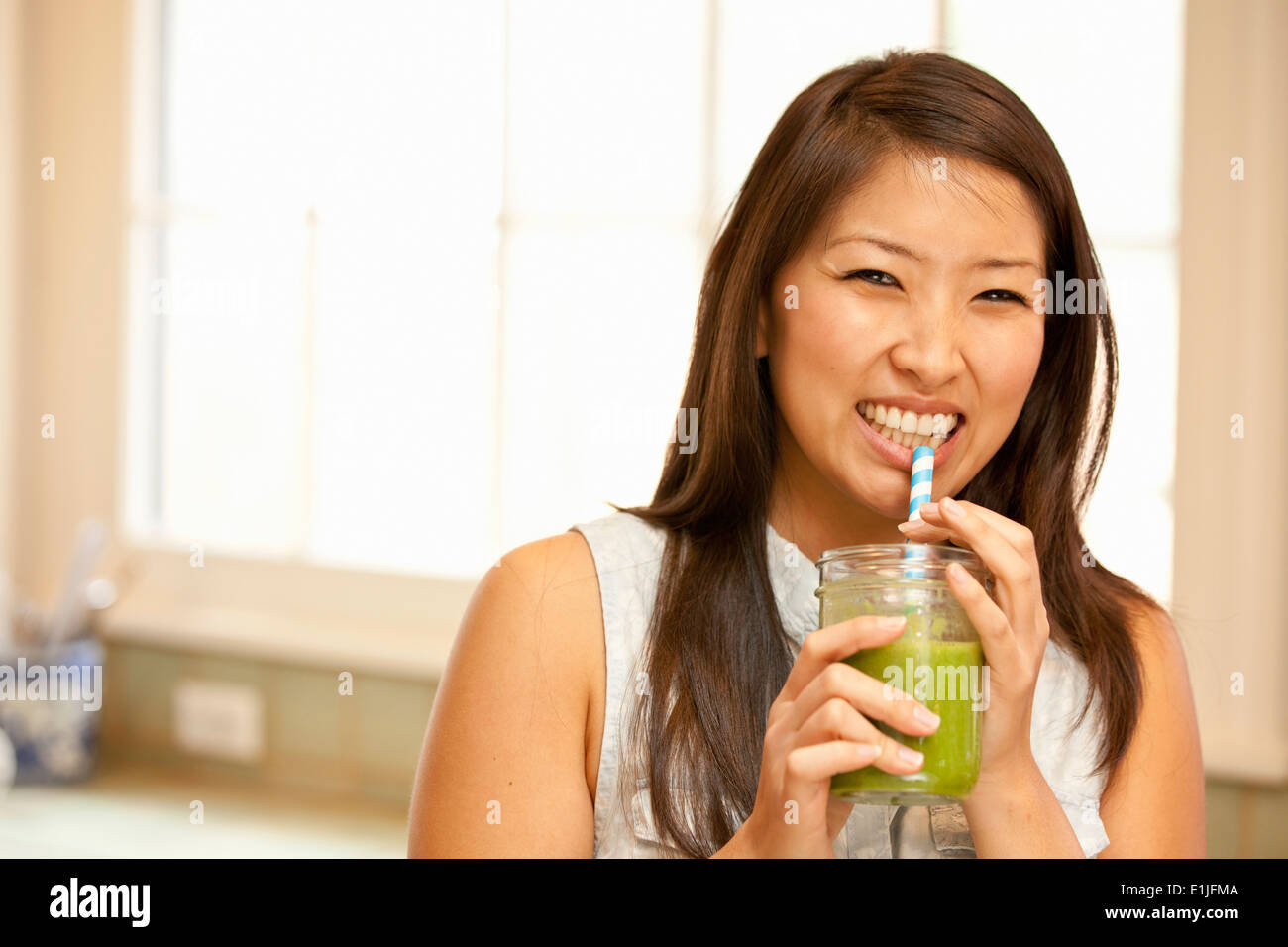 Junge Frau trinken grünen smoothie Stockfoto