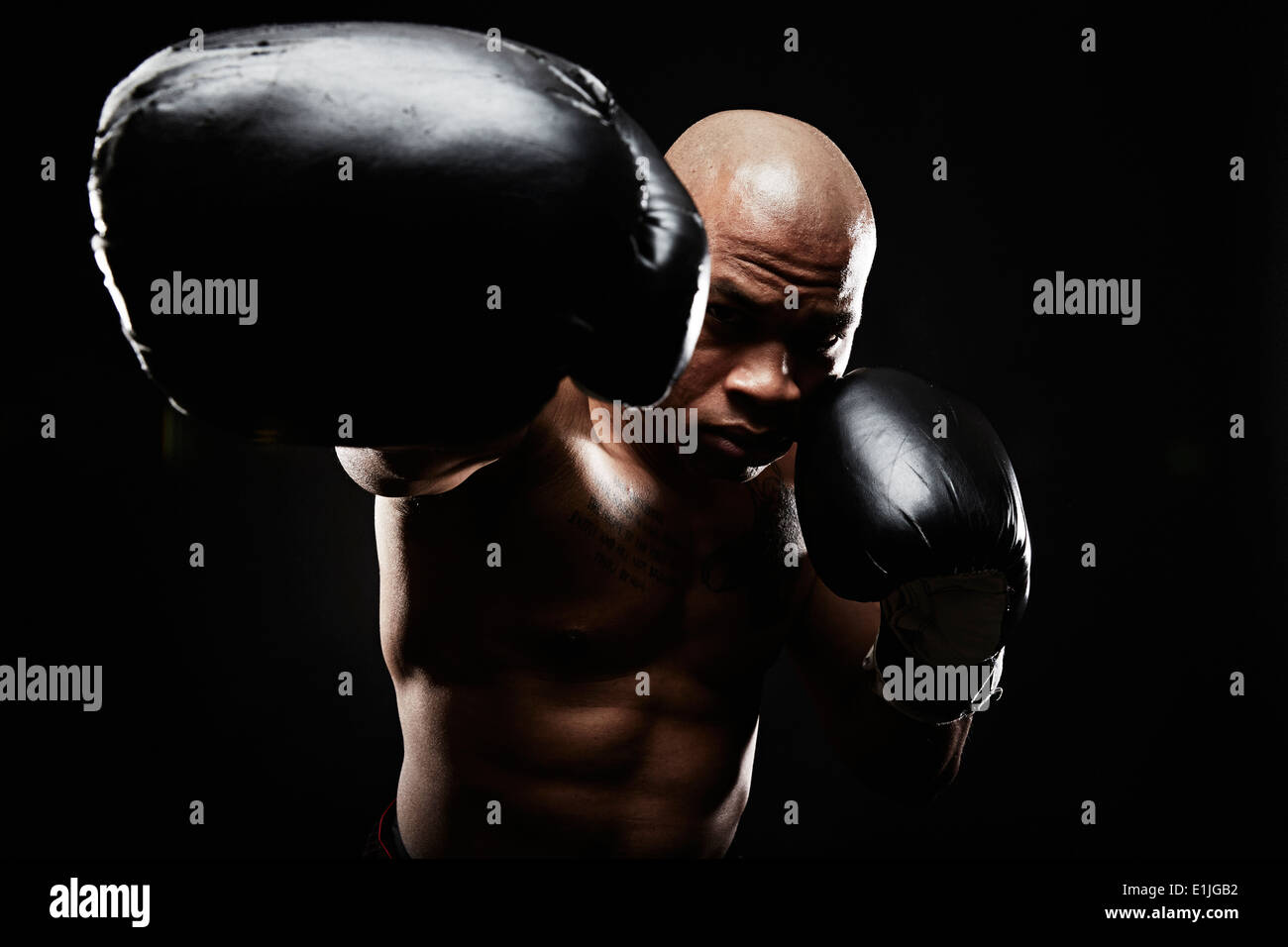 Boxer mit schwarzen Boxhandschuhen Stanzen in Richtung Kamera Stockfoto