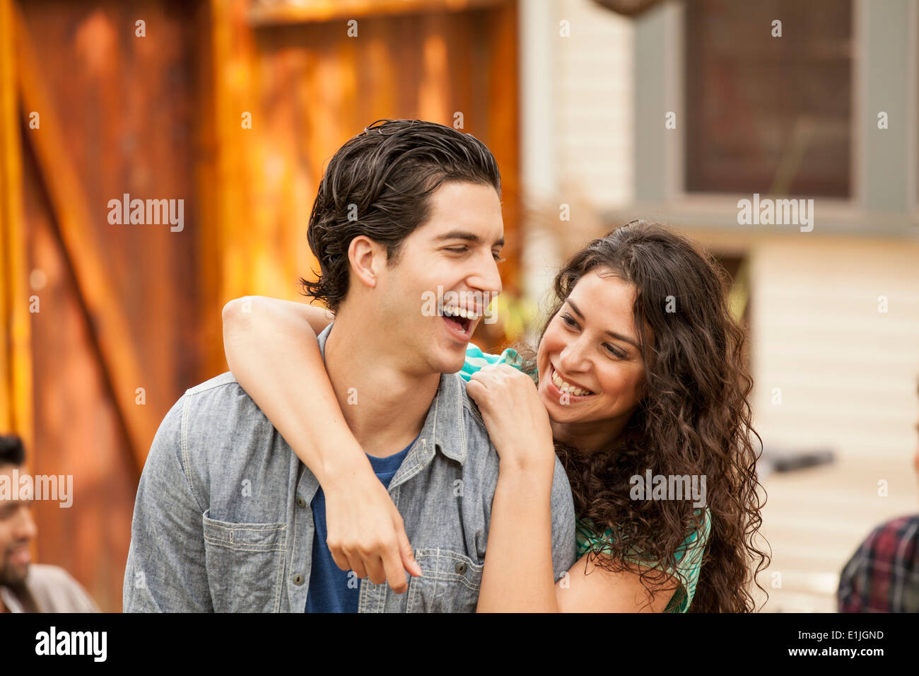 Paar im Garten, mit Arm um Freunde im Hintergrund Stockfoto