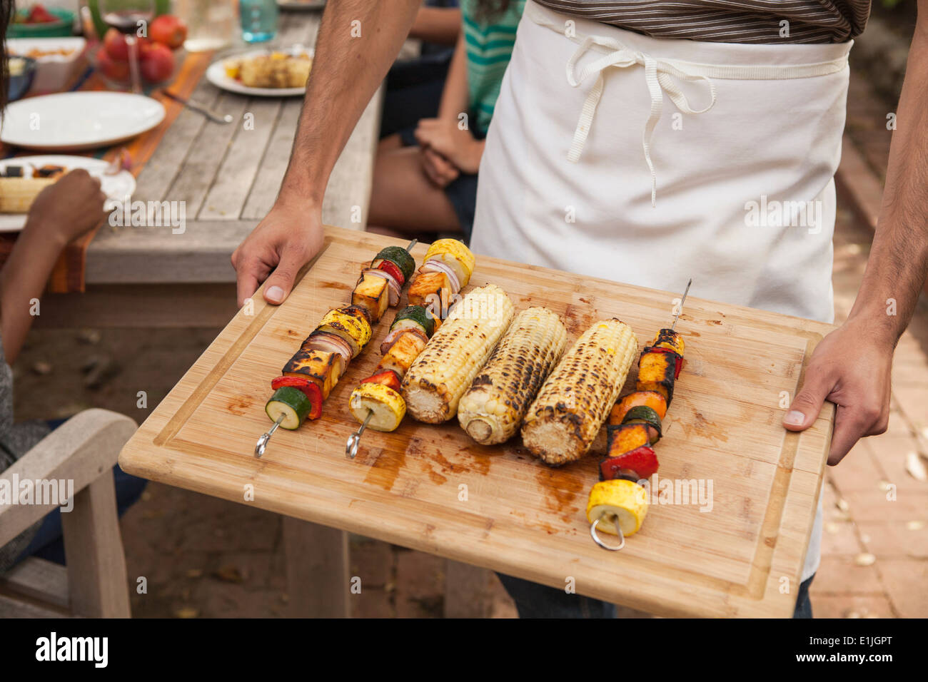 Mann hält Tablett mit gegrilltem Gemüse Spieße und Mais Maiskolben Stockfoto