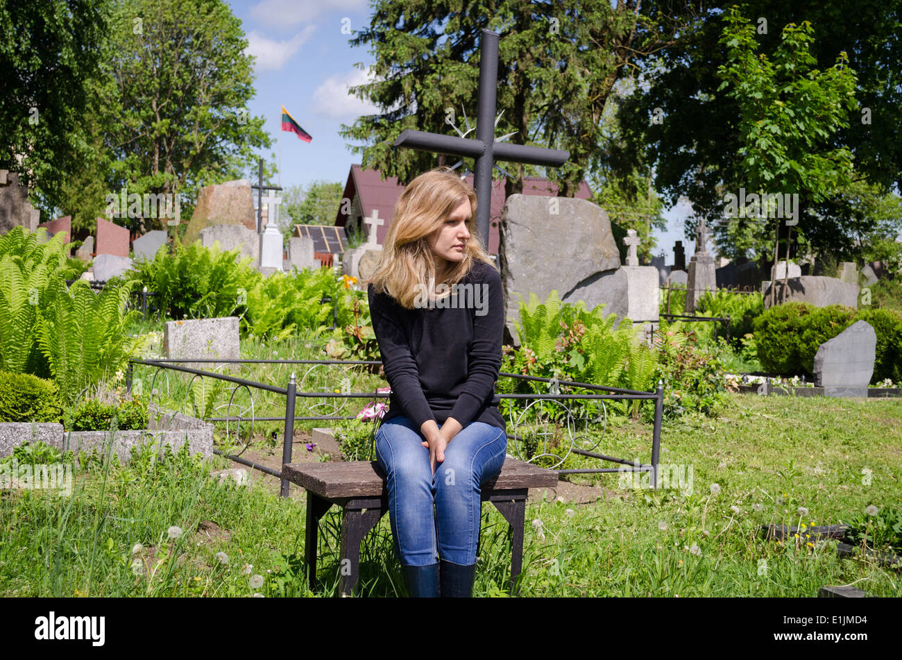 Traurige Frau sitzen in der Nähe von Liebhaber Grab im Friedhof. Patriot Soldat starb. Litauen-Nationalflagge. Stockfoto