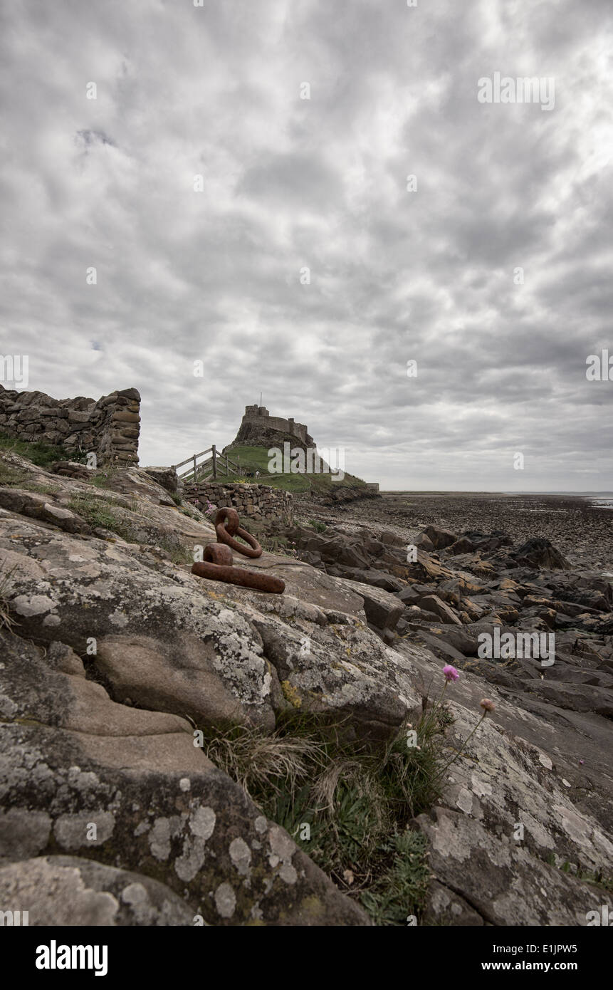 Lindisfarne Schloß vom Ufer entfernt. Rusty Iron Ringe in den Felsen machen den Vordergrund Stockfoto