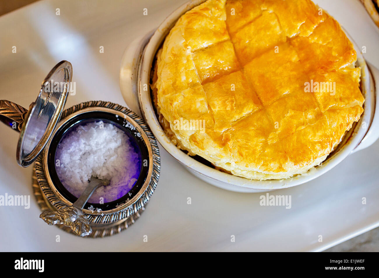 Salz in einem antiken Behälter neben einem hausgemachten Kuchen Hähnchengerichte Stockfoto