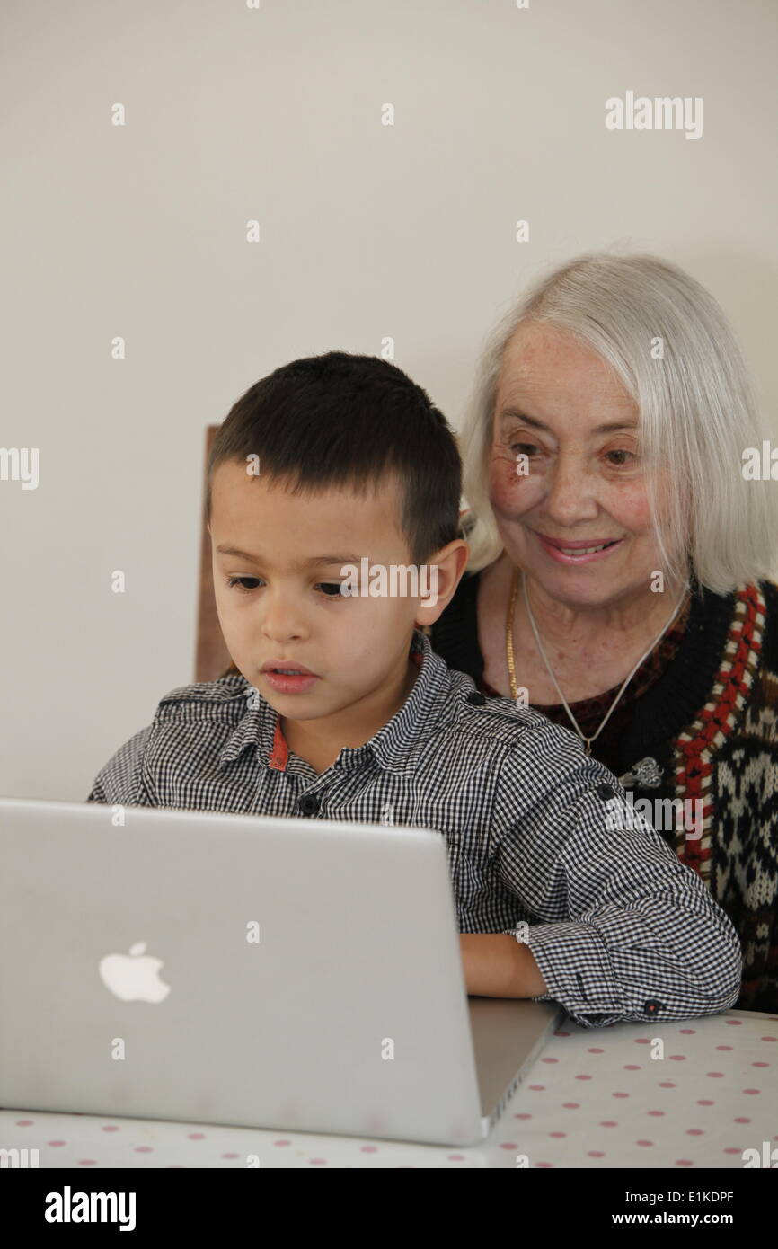 6-jähriger Junge Blick auf einem Laptop mit seiner Großmutter Stockfoto