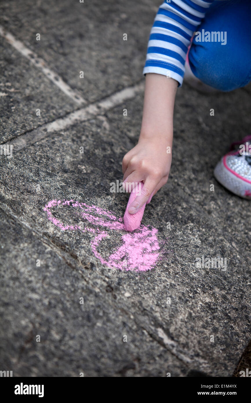 Kind zeichnen ein rosa Kreide Herz auf eine konkrete Bürgersteig. Stockfoto