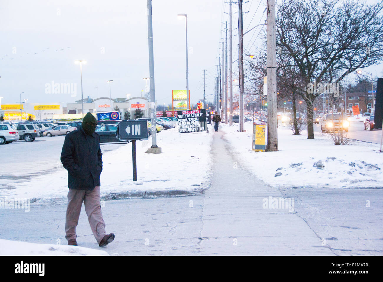 ein Mann seinen Kopf mit warmer Kleidung auf schneit Tag in Toronto zu bedecken. Stockfoto