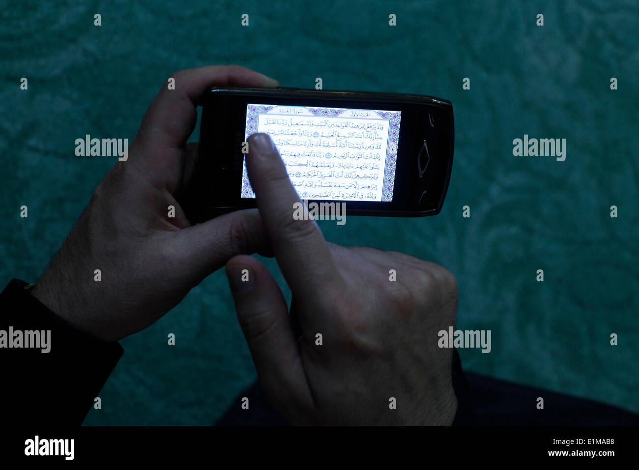 Koran auf einem Handy lesen Stockfoto