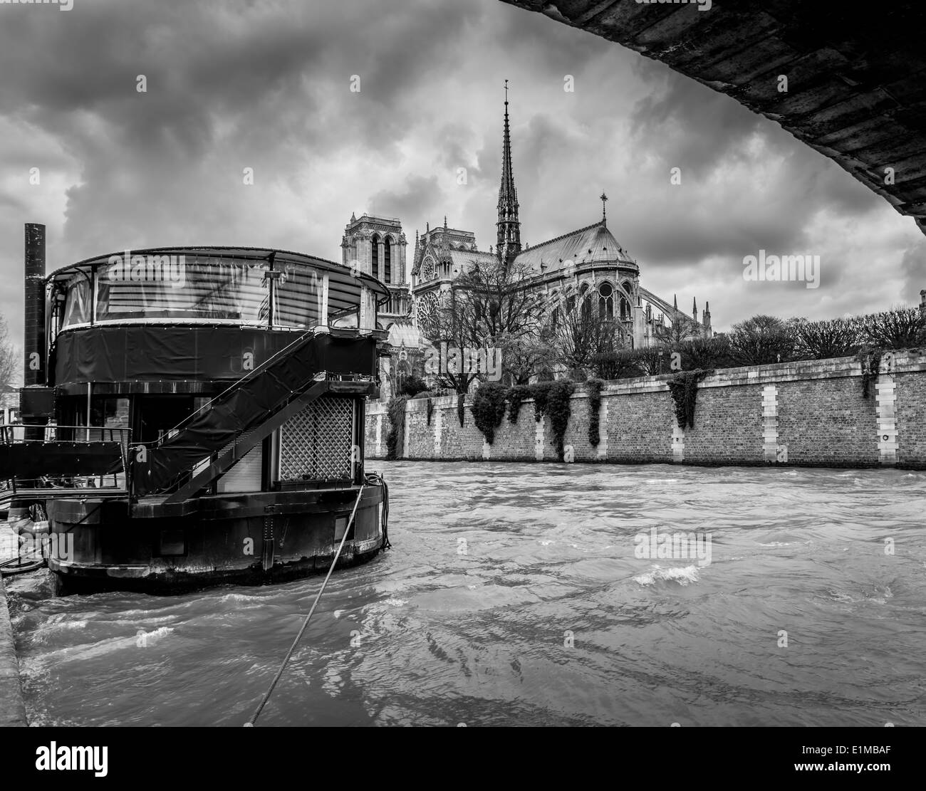 Ein Blick auf die Kathedrale Notre Dame mit einem Boot im Vordergrund wie vom Rand der Seineufer gesehen. Stockfoto