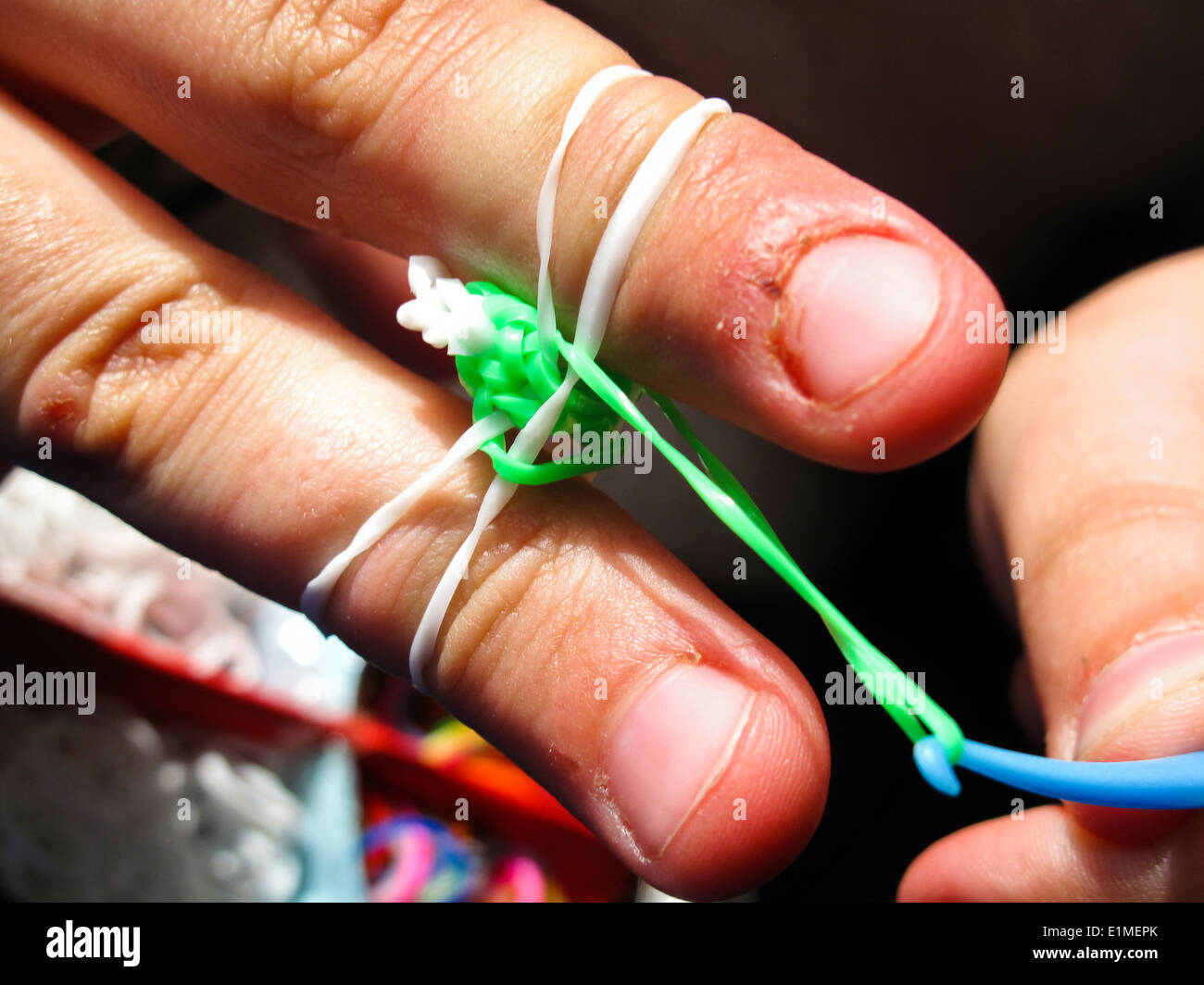 Junge Mädchen, Regenbogen Webstuhl Armband an den Fingern Stockfoto