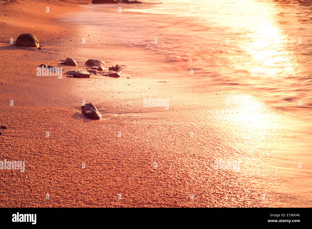 Sand und Wellen bei Sonnenaufgang. Stockfoto