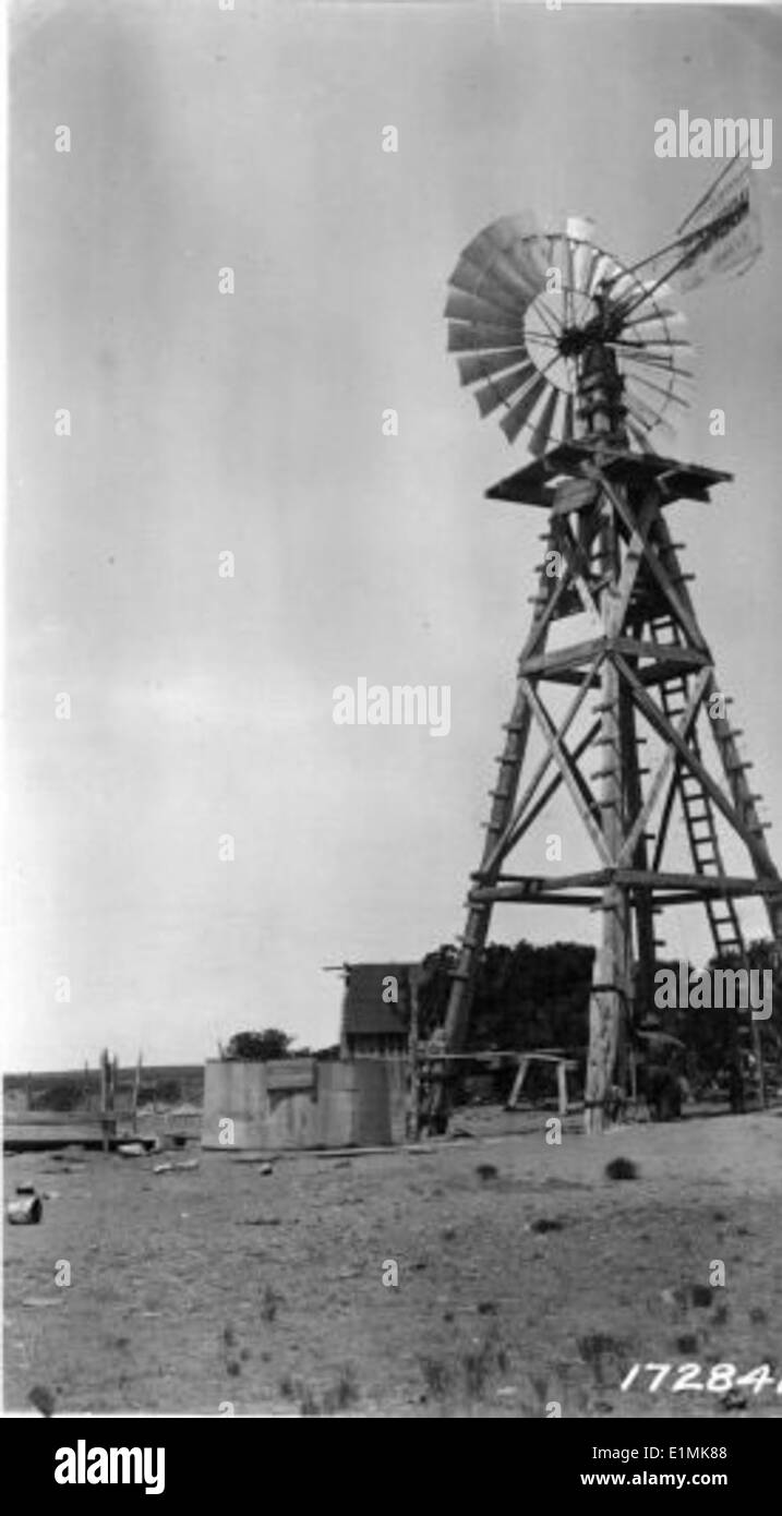 Dieses Schwarzweiß-Foto zeigt eine historische Windmühle, ein Symbol für frühe landwirtschaftliche und Wasserbewirtschaftungspraktiken. Windmühlen waren für die Wasserversorgung sowohl für die Landwirtschaft als auch für die Viehzucht in ländlichen Gemeinden von entscheidender Bedeutung. Stockfoto