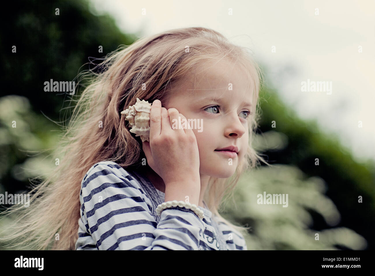 Kind, lauschen Sie den Klängen einer Muschel. Stockfoto