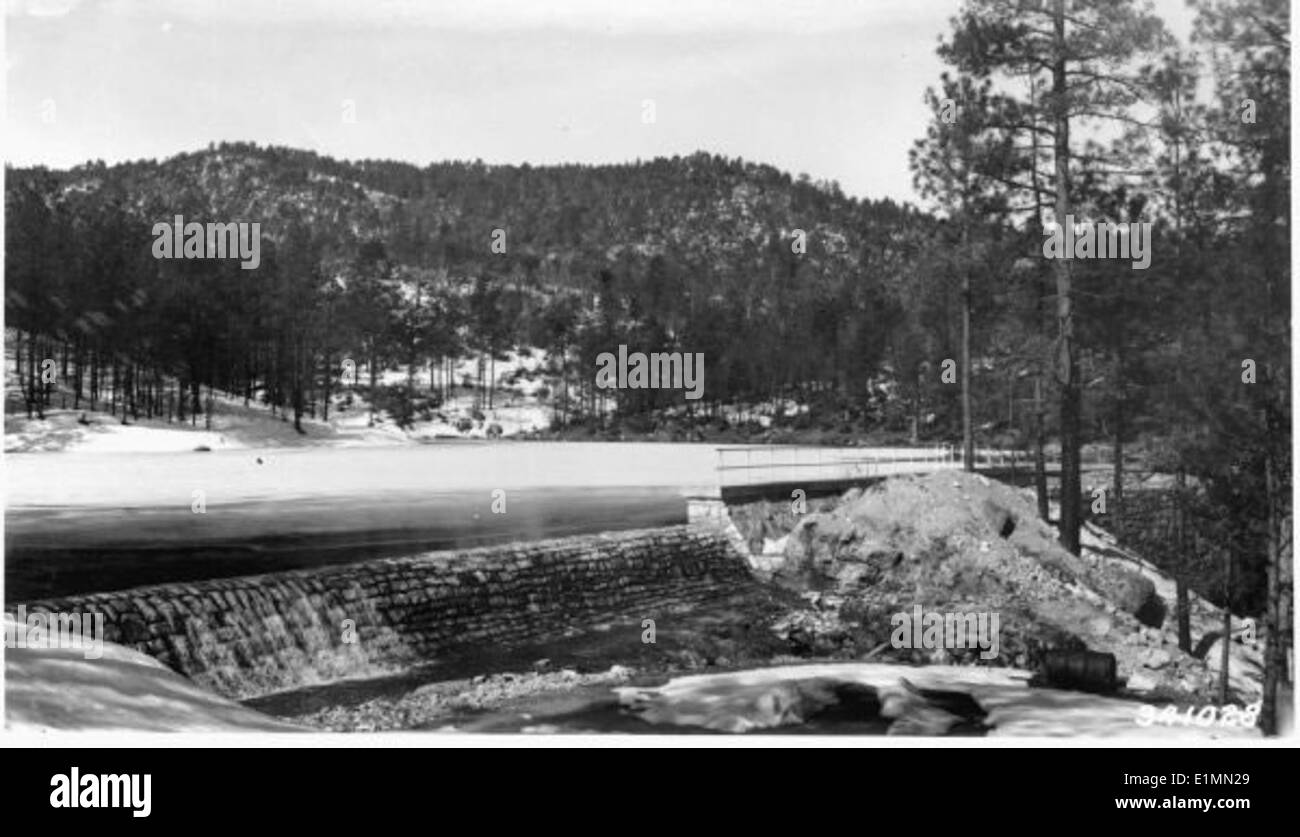 Ein Schwarzweißbild, das die Landschaft des Prescott Forest mit Bäumen, Wasser und einem historischen Damm im Vordergrund zeigt. Die umliegenden Berge verstärken die natürliche Schönheit und historische Bedeutung des Ortes. Stockfoto