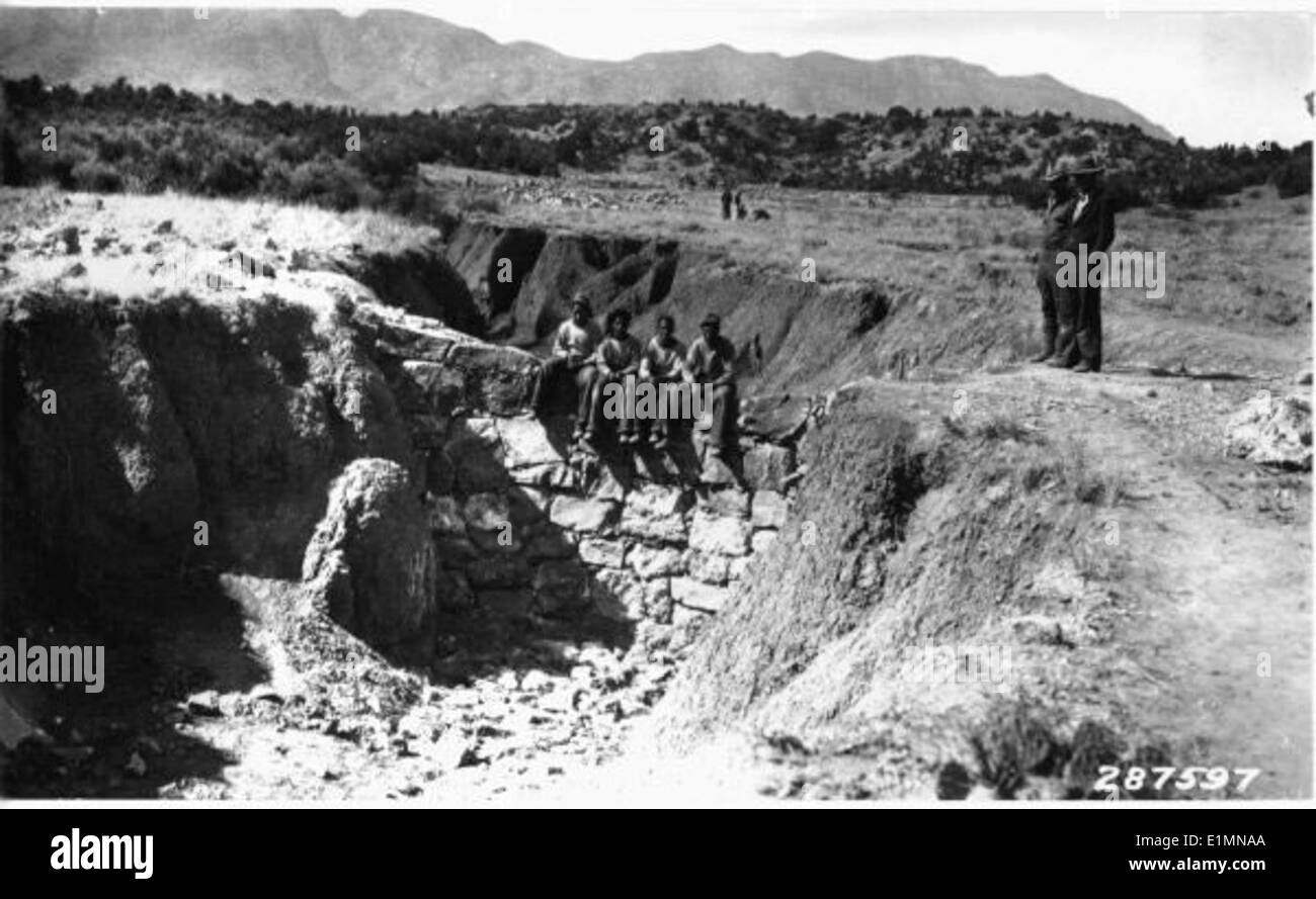 Dieses Schwarzweiß-Bild zeigt die Erosion im Prescott National Forest, wo sich menschliche Aktivitäten und natürliche Prozesse überschneiden. Die historische Damm- und Berglandschaft veranschaulicht die Rolle des Waldes bei der Wasserbewirtschaftung und der Erhaltung des Ökosystems. Die Erosion in diesem Gebiet ist ein anhaltendes Problem, das sich auf die Bodengesundheit und die Wasserqualität auswirkt. Das Bild zeigt sowohl ökologische Herausforderungen als auch menschliche Eingriffe in die Waldbewirtschaftung. Stockfoto
