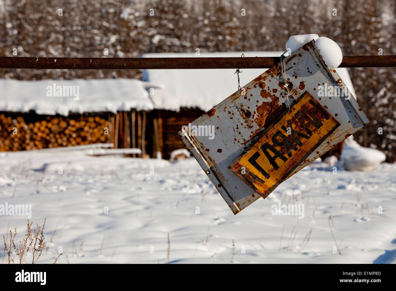 rostige russischen Schild hängen schief Schnee Bäume Protokolle Stockfoto