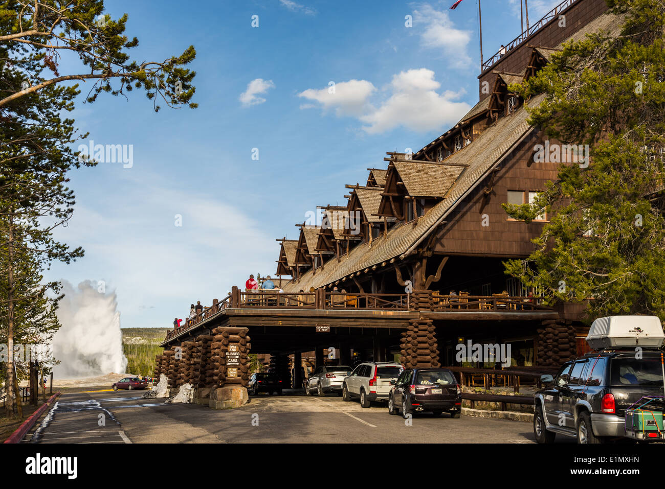 Die historischen Old Faithful Inn, mit der Old Faithful Geysir ausbrechen im Hintergrund. Yellowstone-Nationalpark, Wyoming, USA. Stockfoto