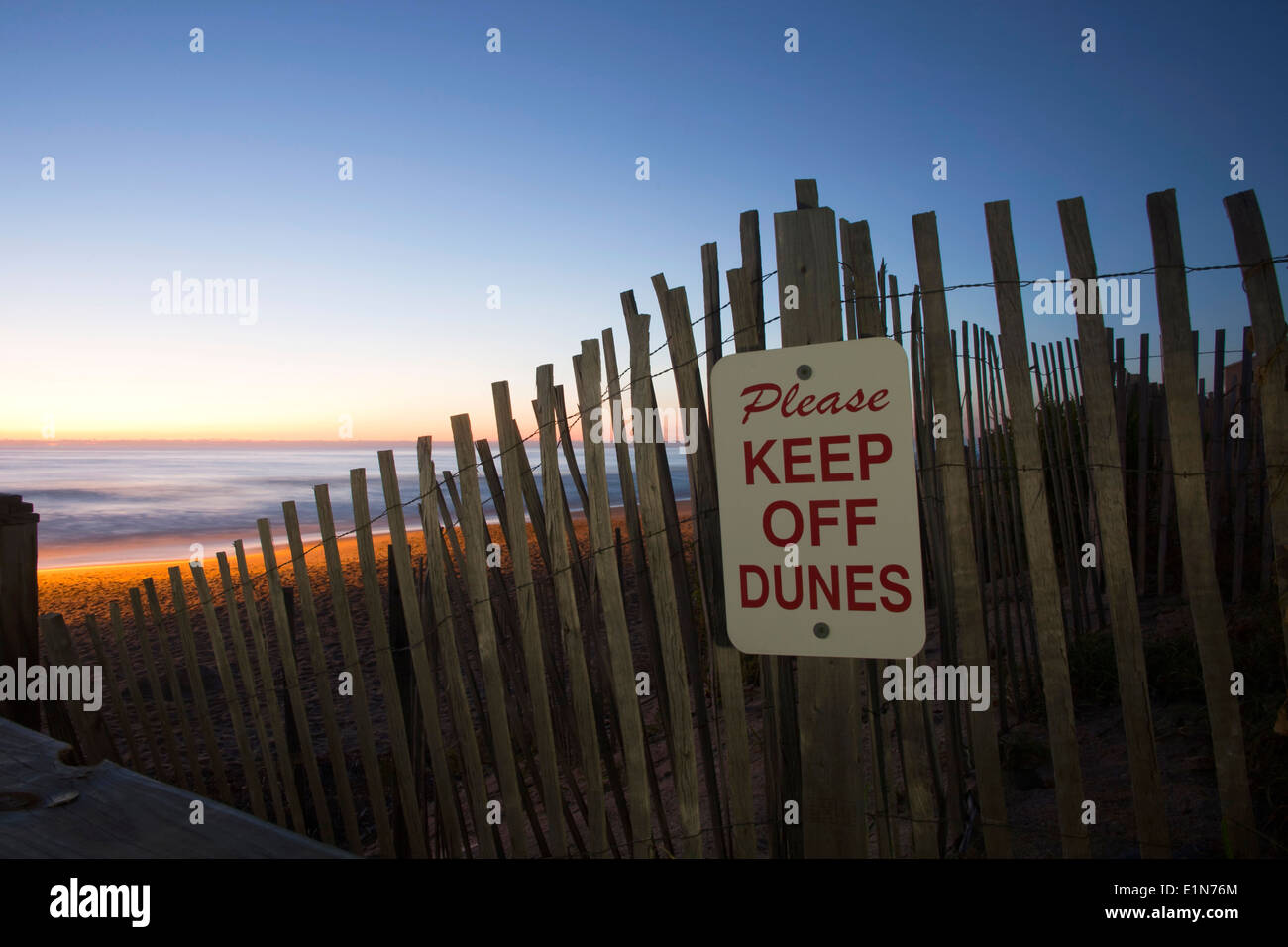 Sonnenaufgang über den Strand mit Schild auf dem Zaun erinnern Menschen weg von den Dünen Stockfoto