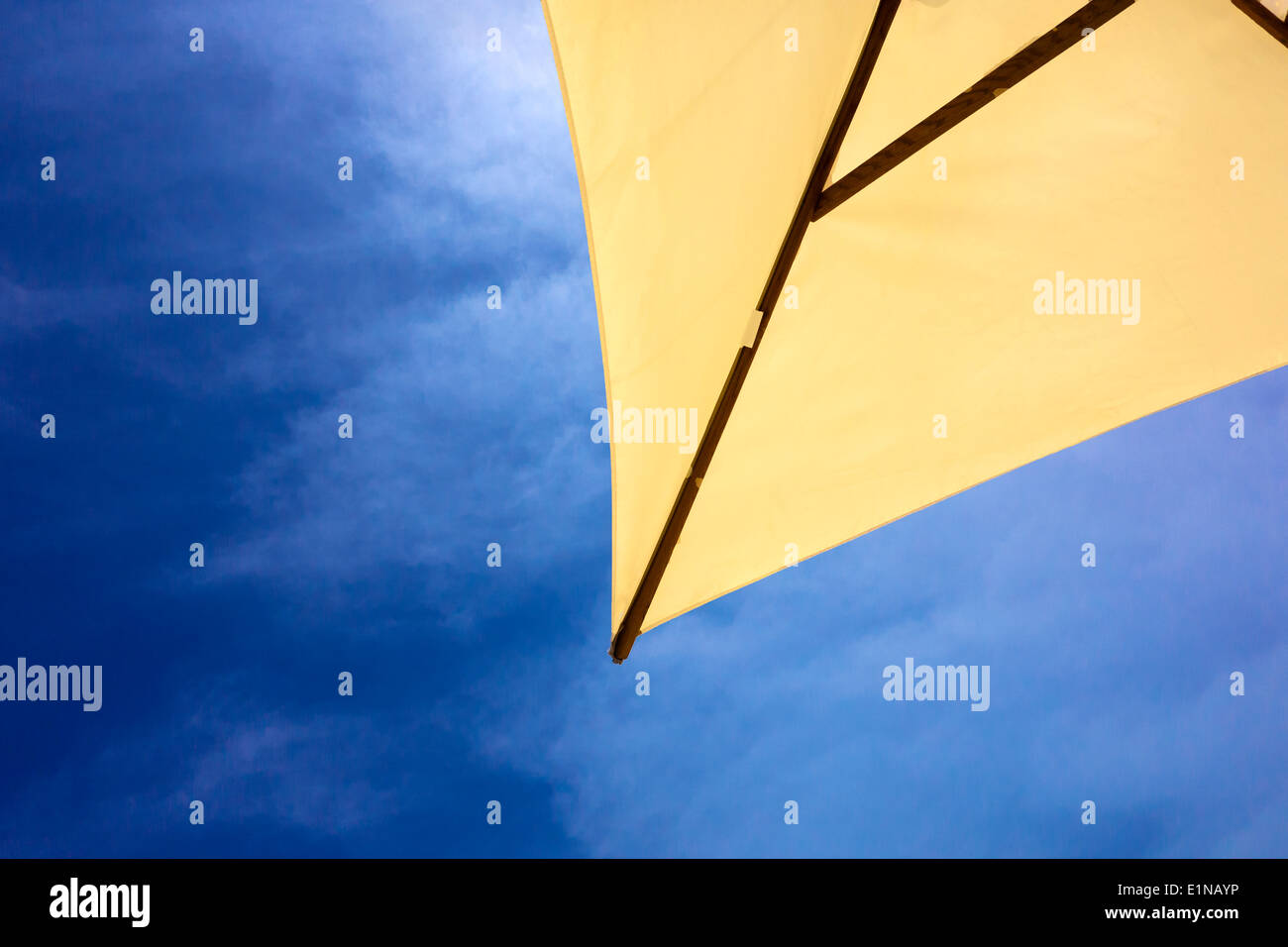Gelbe Sonnenschirm vor einem blauen Himmel mit einigen dünnen, wispy Cloud. Stockfoto