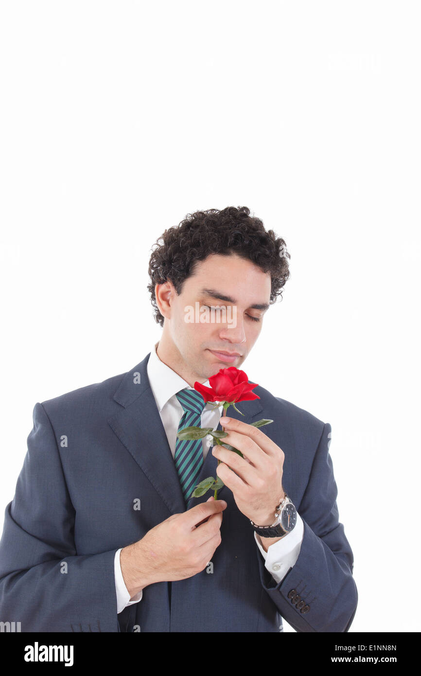 gut aussehender Mann Verführer in einem Business-Anzug rose in der Hand halten und riechen, isoliert auf weißem Hintergrund Stockfoto