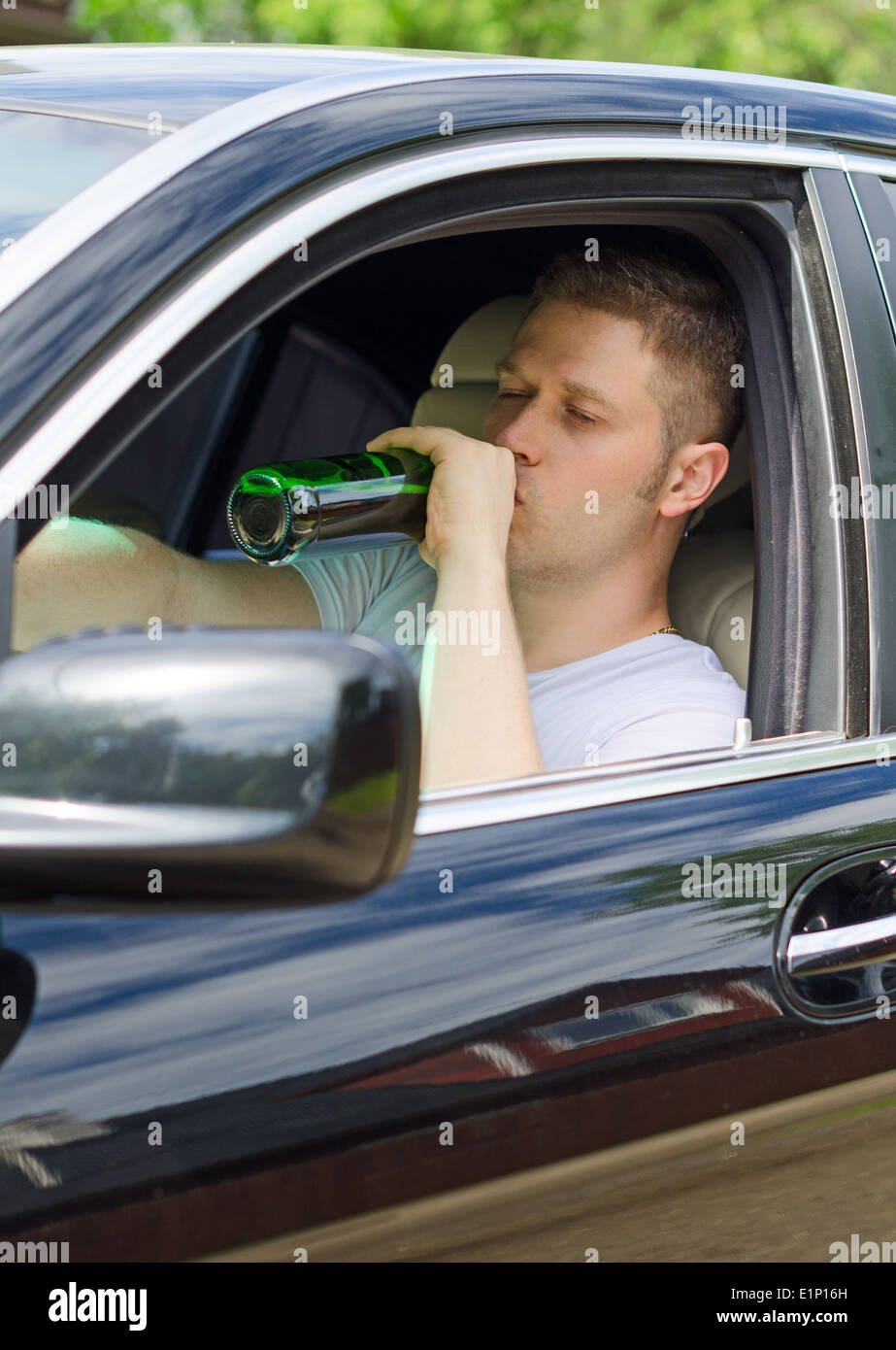 Fahren unter dem Einfluss. Menschen trinken Alkohol im Auto. Stockfoto