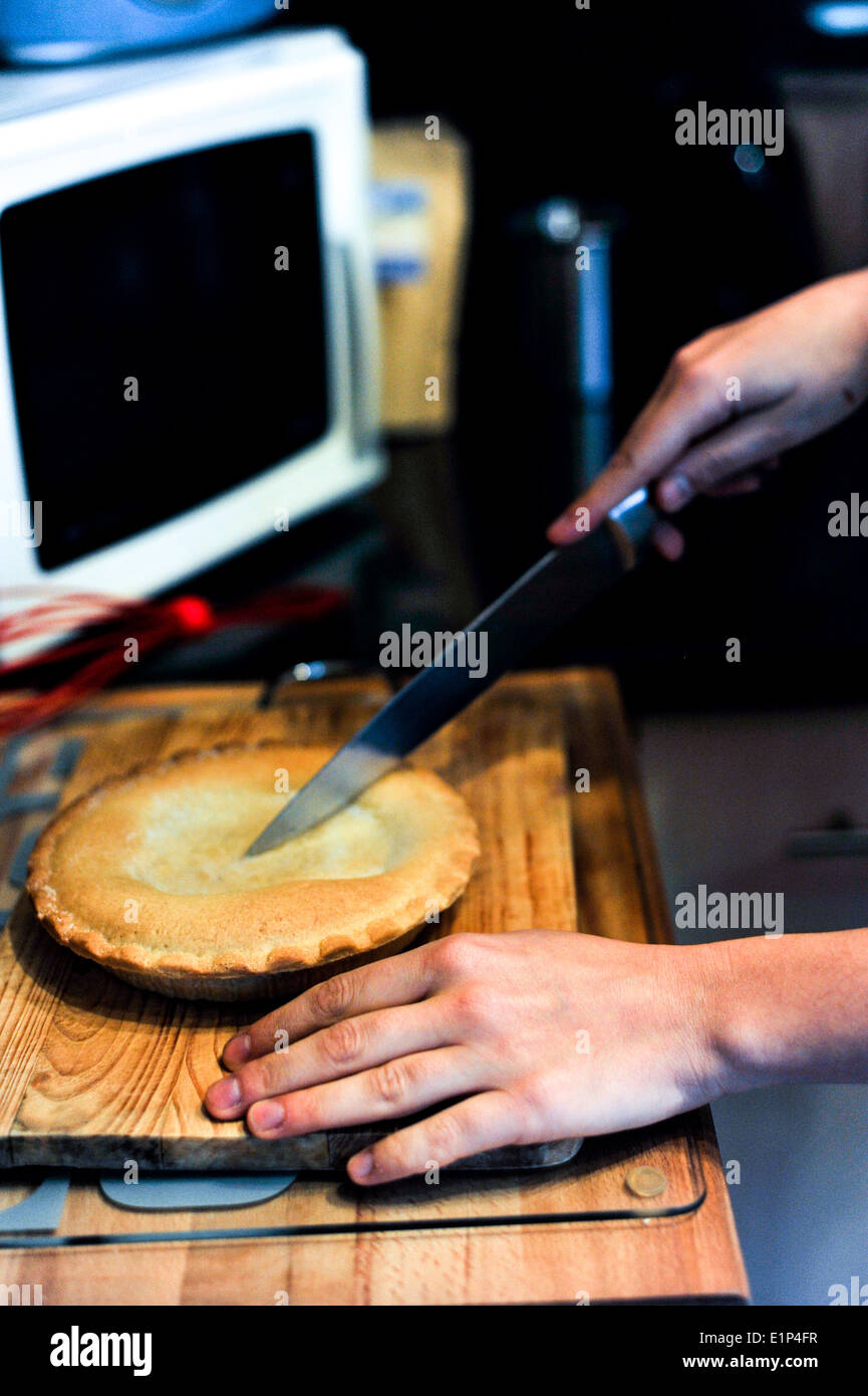 Hand, die einen Kuchen mit einem Messer schneiden Stockfoto