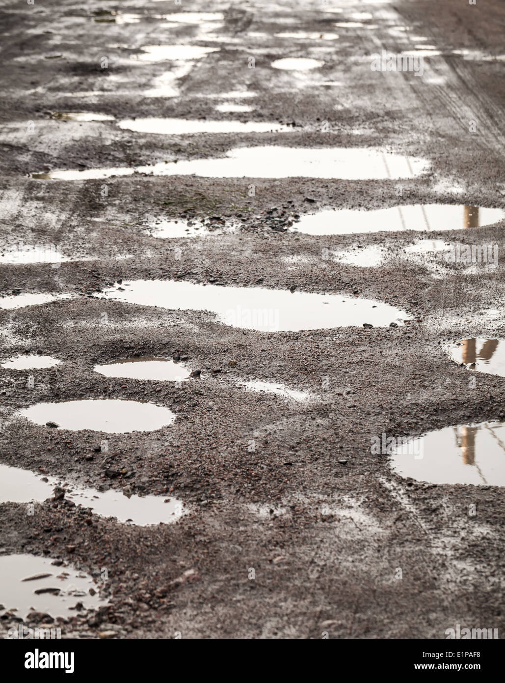 Schmutzige beschädigte Landstraße mit Muds und Löcher Stockfoto