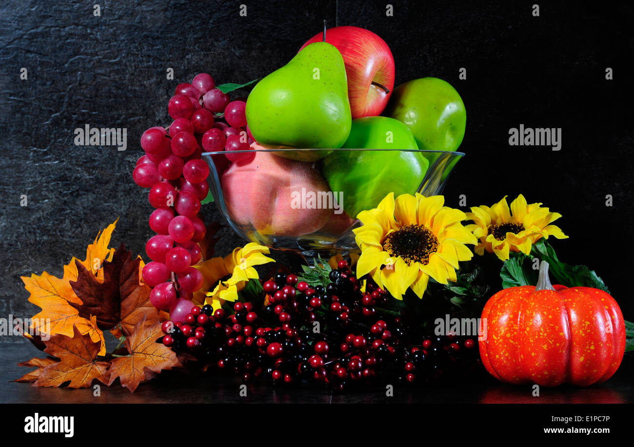 Herbst Herbst Stilleben Schüssel mit Früchten, Blüten und Beeren gegen einen dramatischen schwarzen Schiefer Küchenbank top Hintergrund. Stockfoto