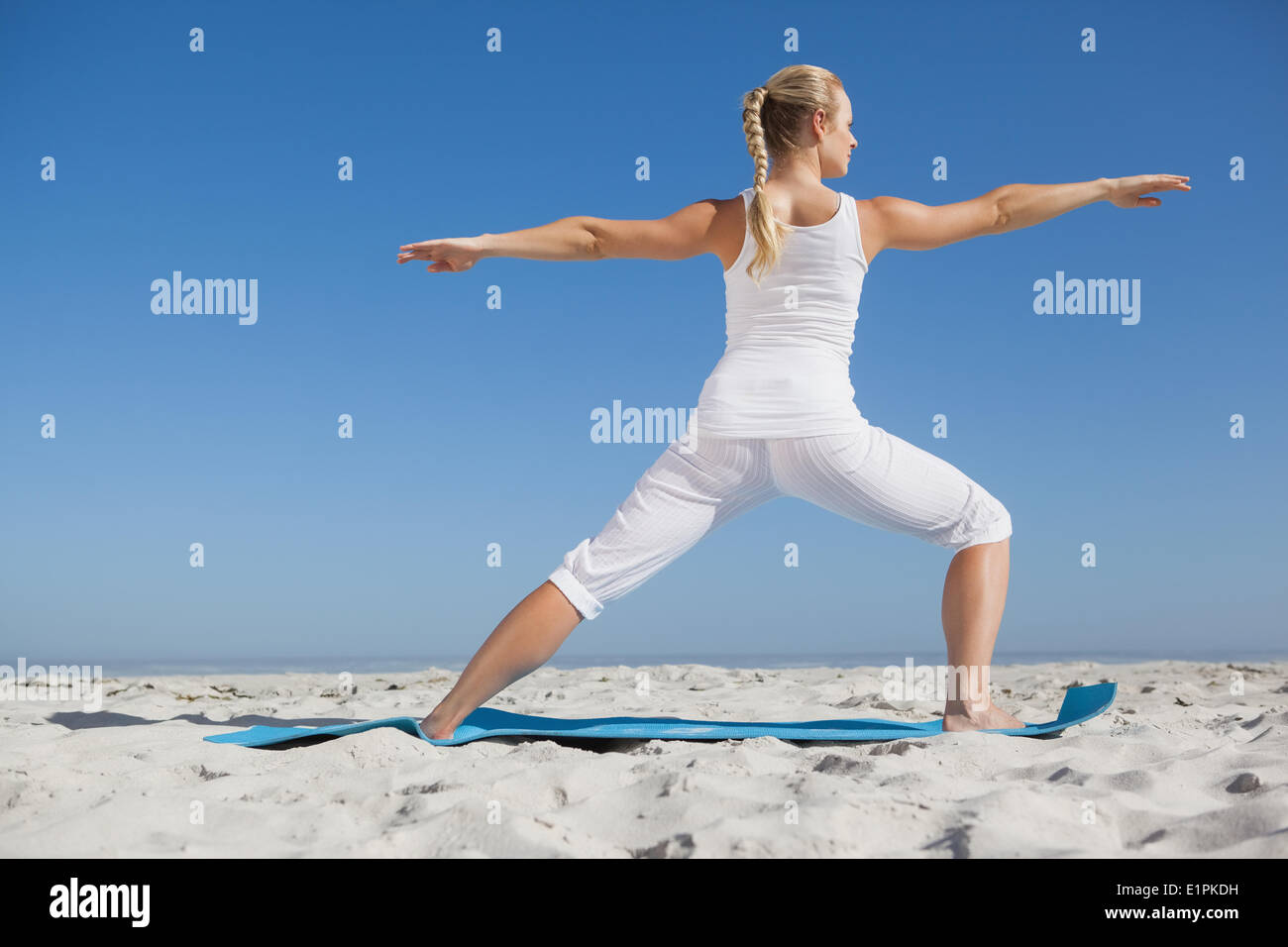 Ruhige Frau im Krieger-Pose am Strand Stockfoto