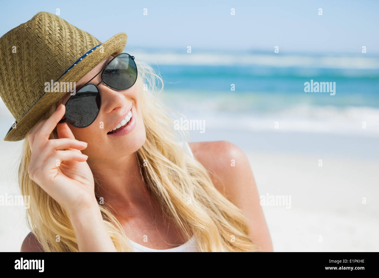 Stilvolle Blondine lächelnd am Strand Stockfoto
