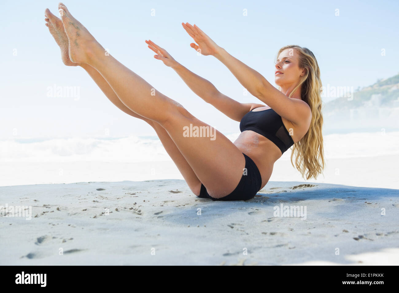 Fit Blondine im Kern Gleichgewicht darstellen Pilates am Strand Stockfoto
