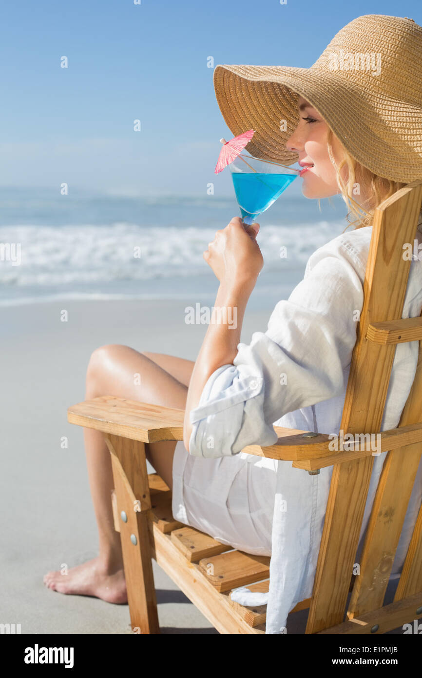 Lächelnde blonde entspannen im Liegestuhl am Meer cocktail schlürfen Stockfoto