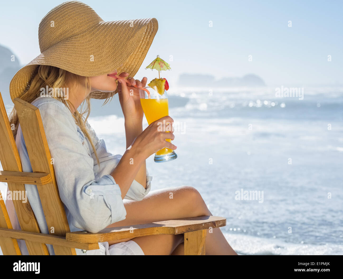 Lächelnde blonde entspannen im Liegestuhl am Meer cocktail schlürfen Stockfoto