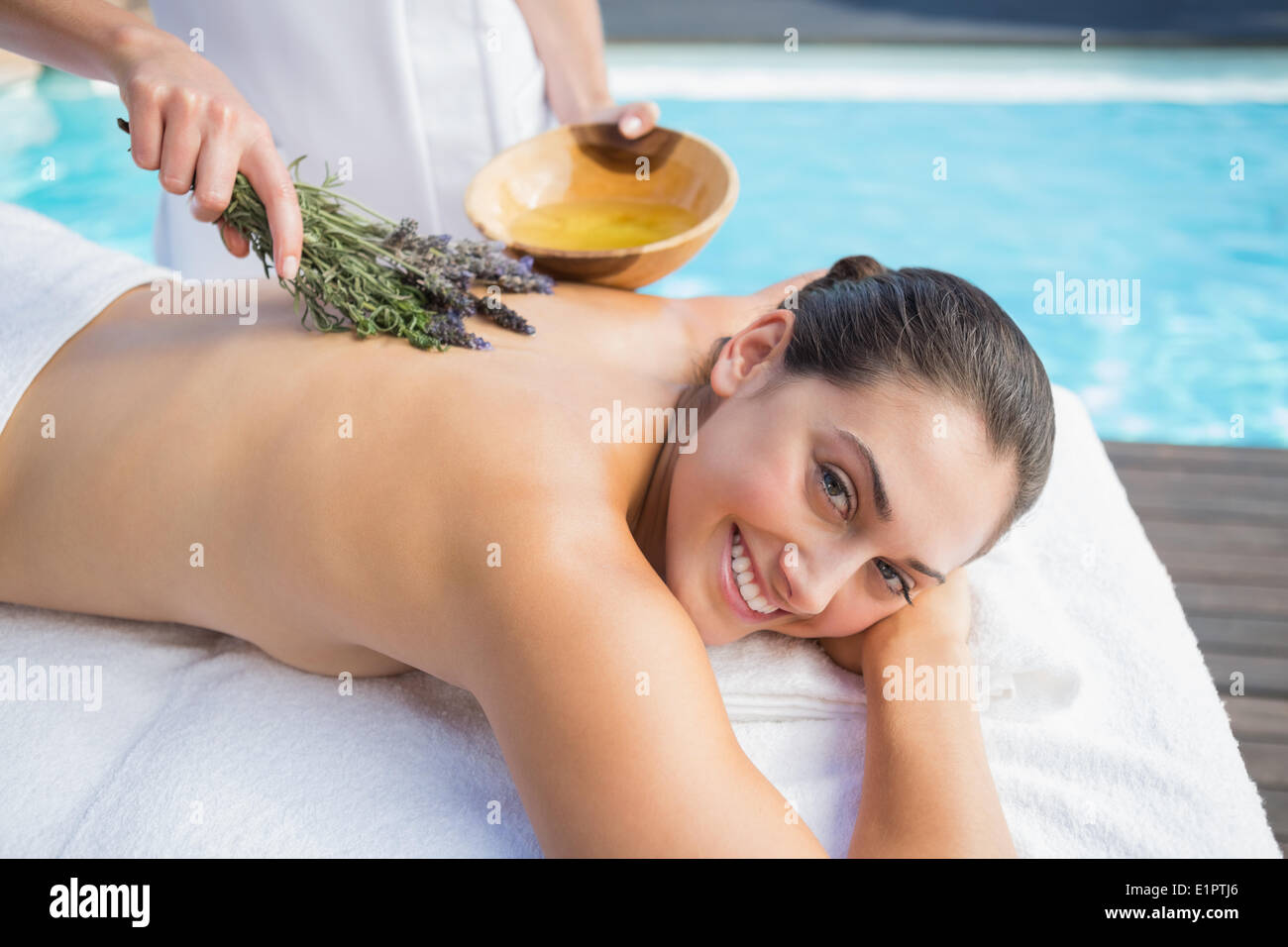 Lächelnde Frau, die immer eine Aromatherapie-Behandlung am Pool Stockfoto