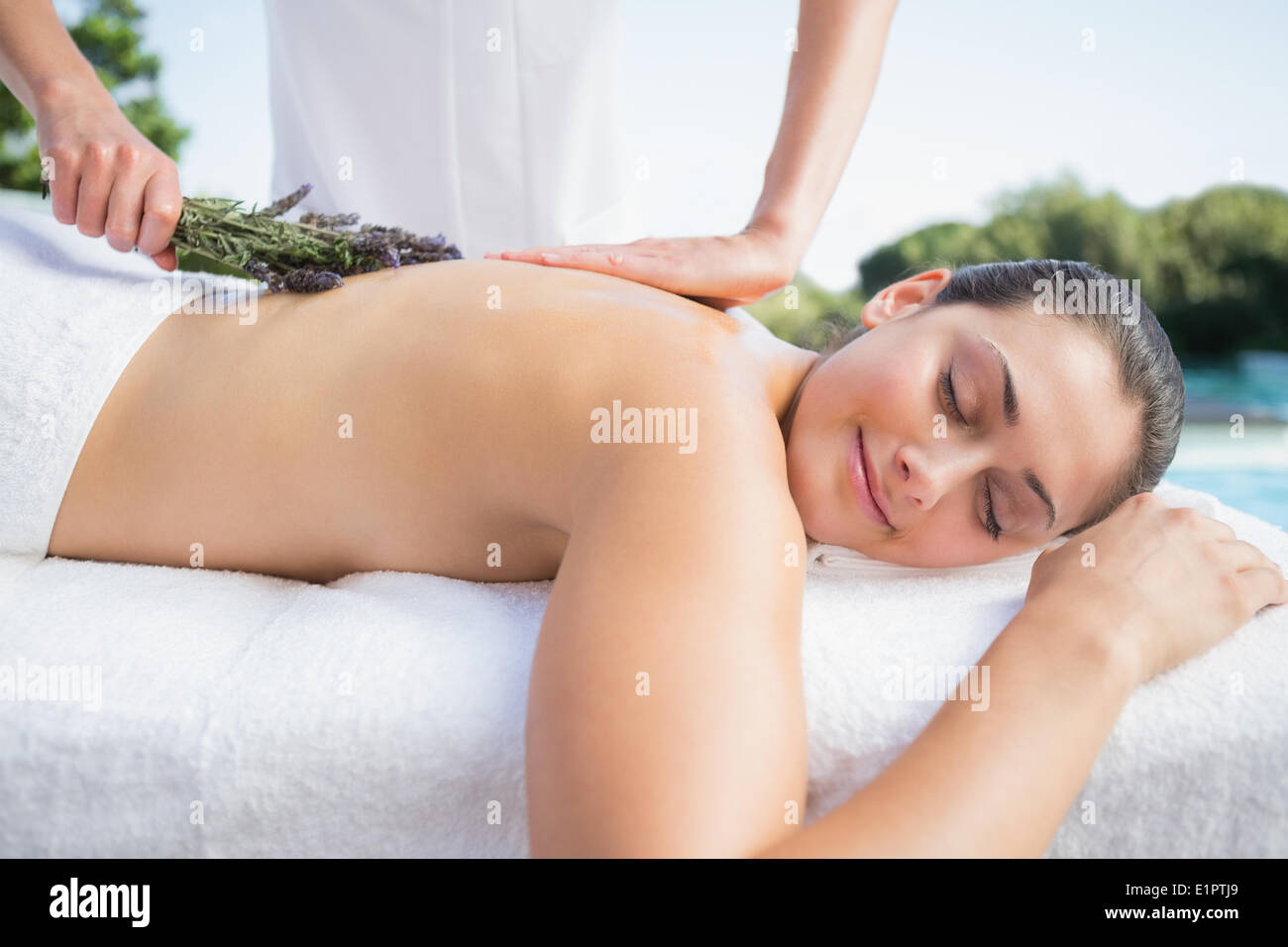 Lächelnde Brünette immer eine Aromatherapie-Behandlung am Pool Stockfoto