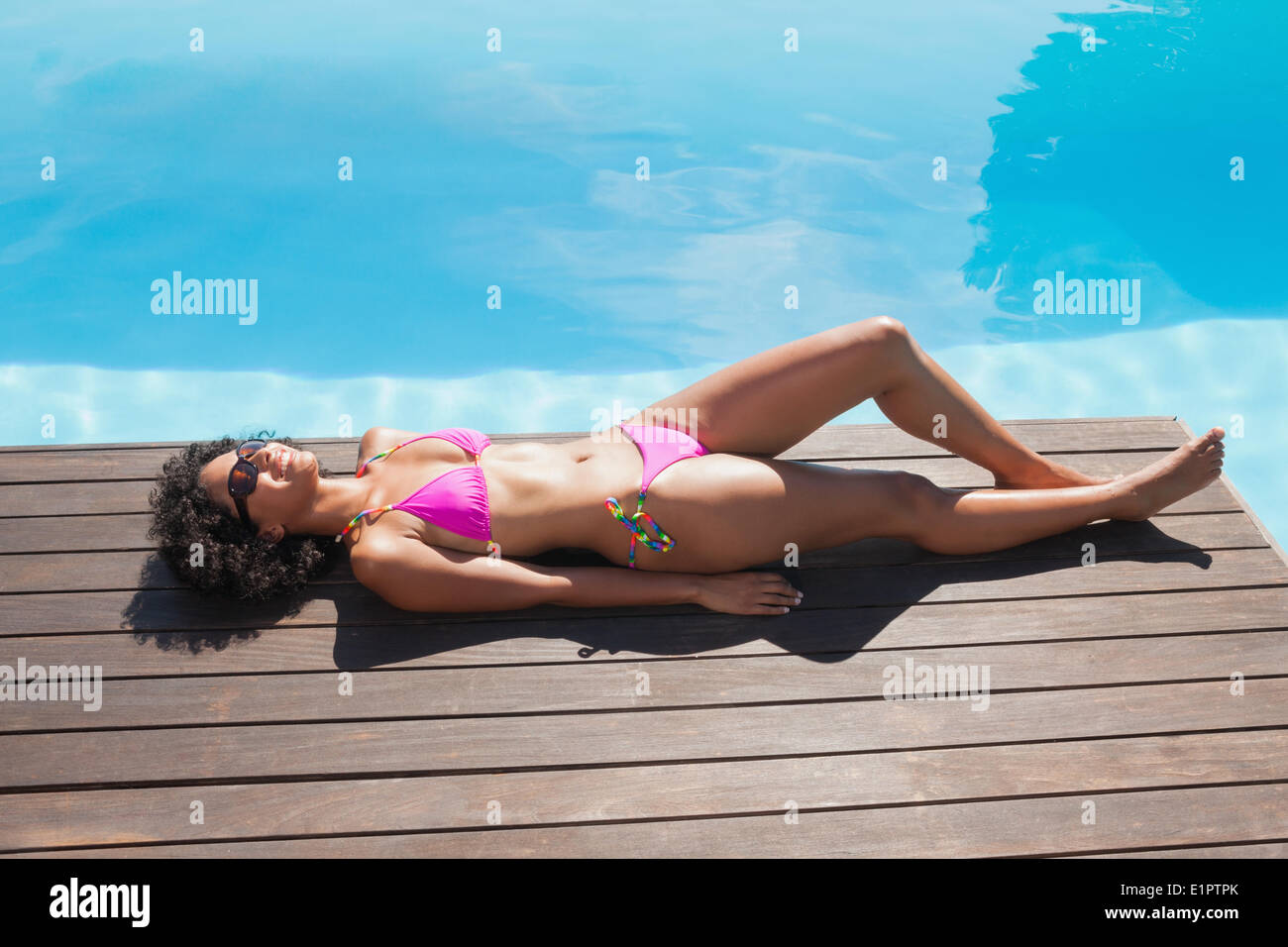 Fit Woman in rosa Bikini liegen am Pool Stockfoto