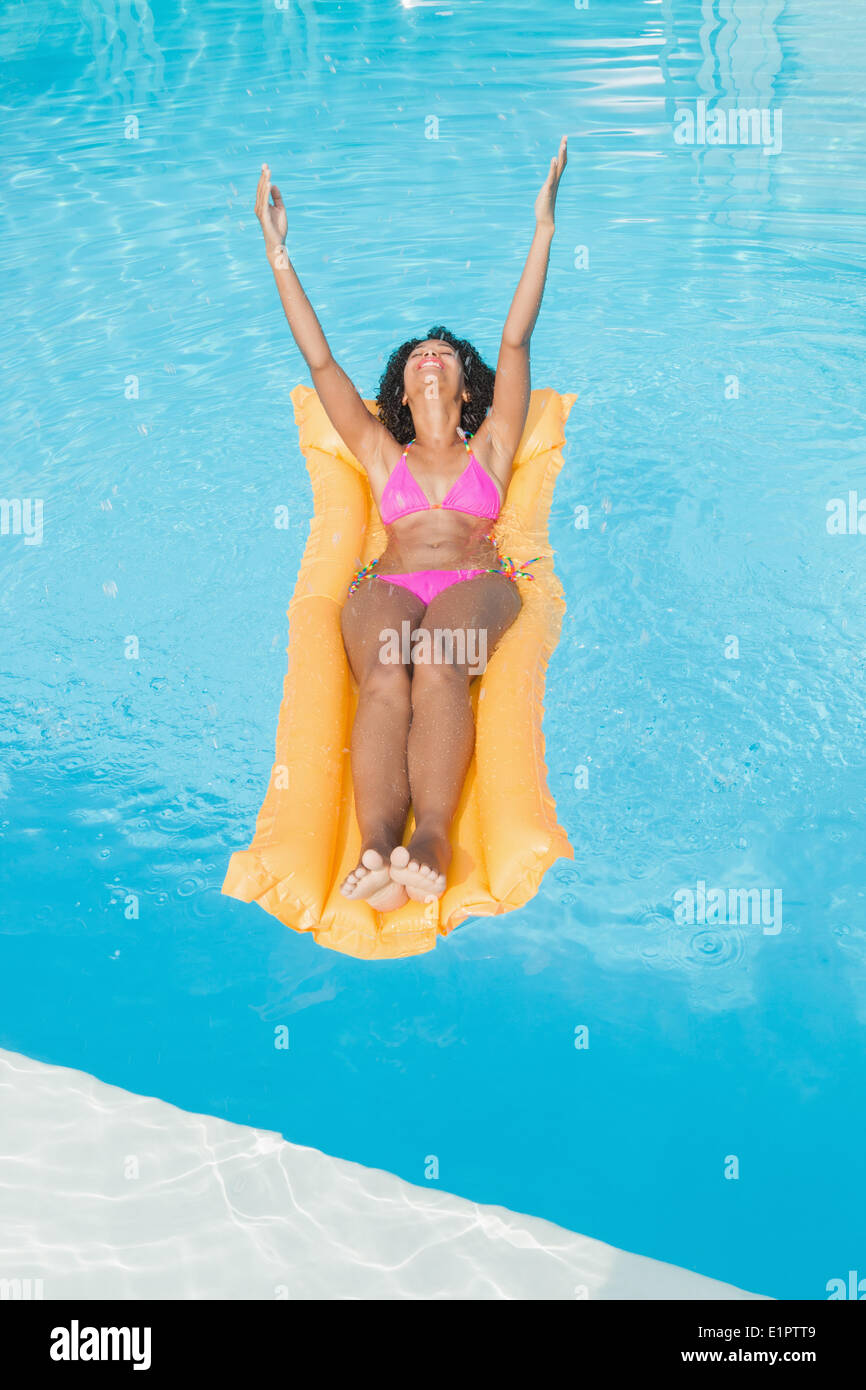 Erregte Frau in rosa Bikini liegen auf Lilo im Schwimmbad Stockfoto