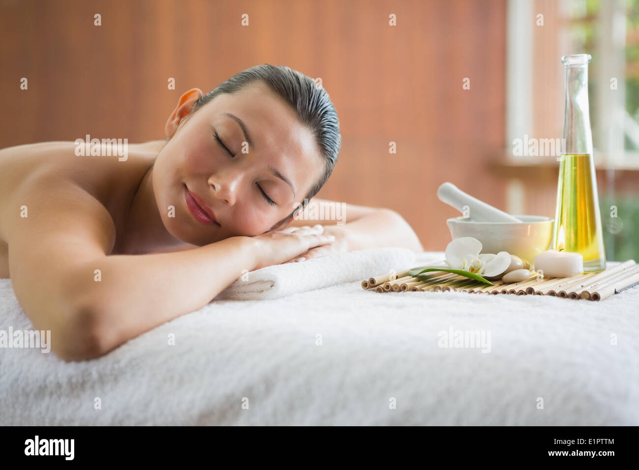 Brünette auf Massagetisch liegend mit Tablett mit Beauty-Behandlungen Stockfoto